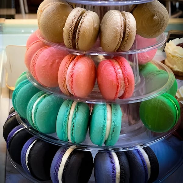 A tiered display of colorful macarons in brown, pink, teal, green, black, and purple.